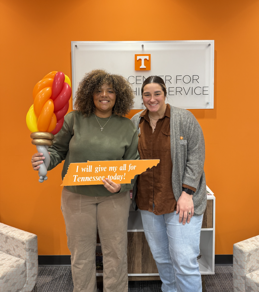 Genesis Nolan holding an I will give my all for Tennessee Today! sign and balloon art of a torch